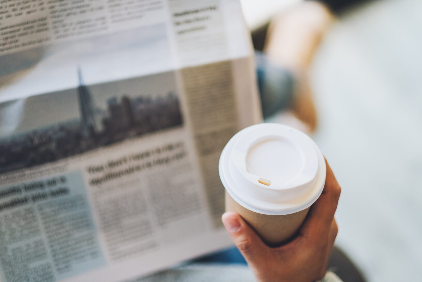 Femme lisant un journal avec un café à la main